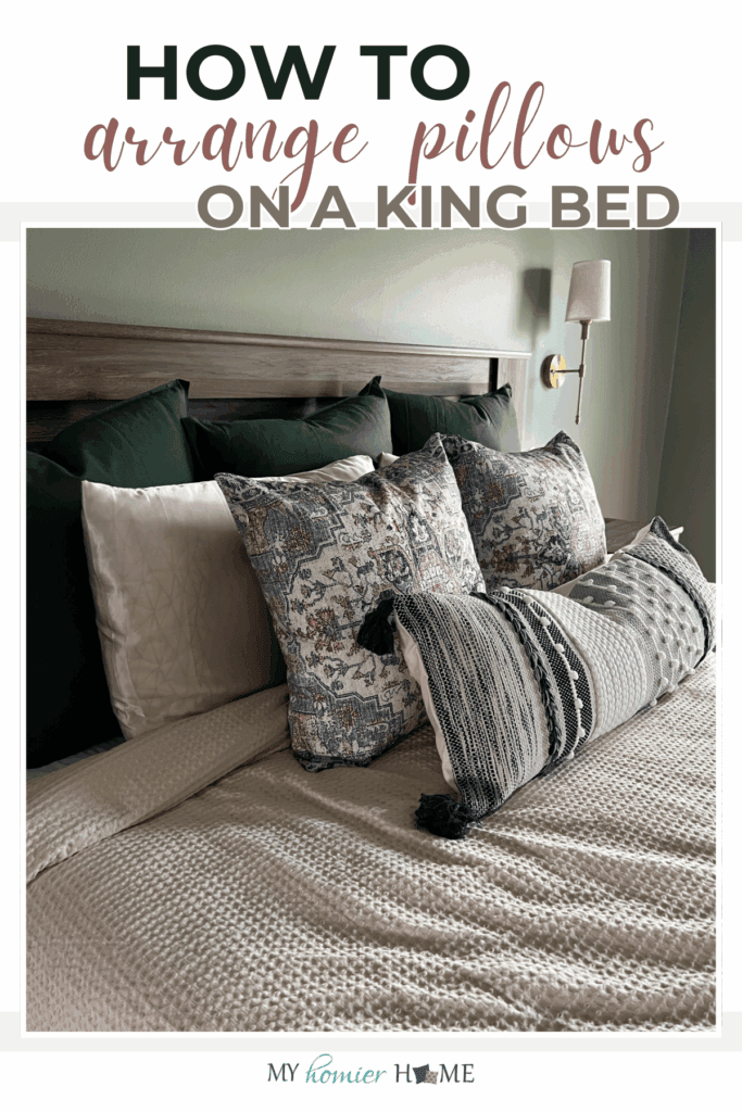 A king bed with dark green, patterned, and textured pillows arranged in layers against a wooden headboard, showcasing how to arrange pillows on a king bed.