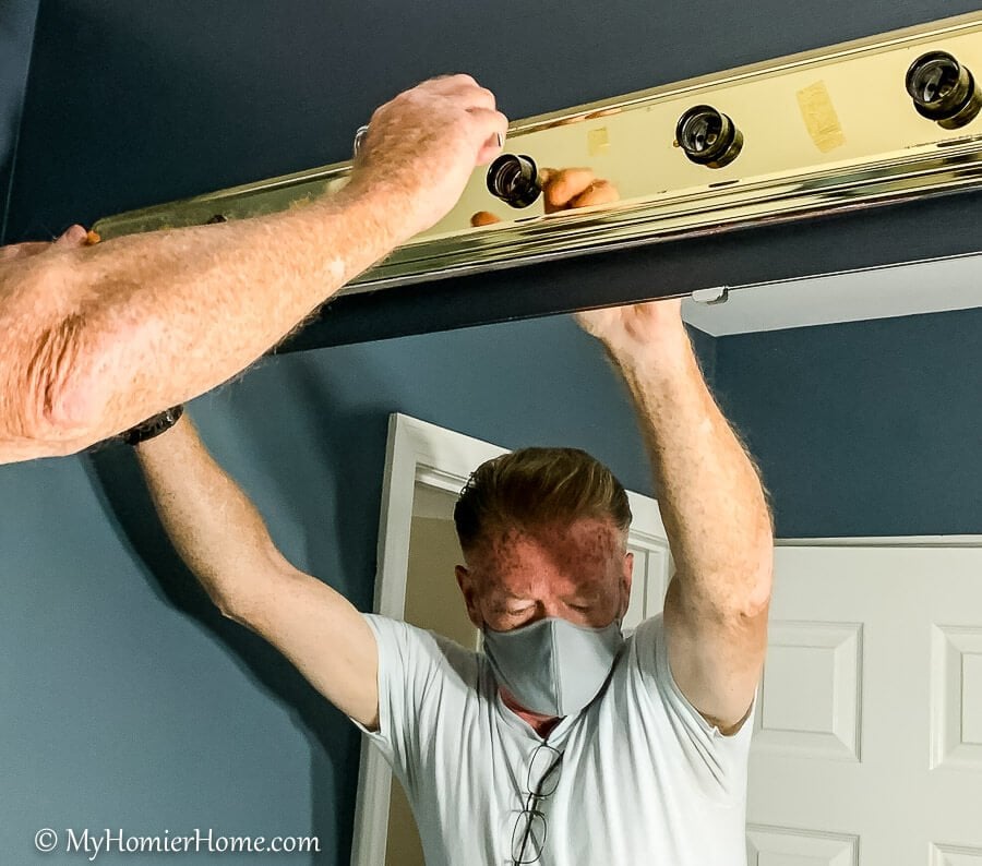 man removing light fixture pieces to spray paint