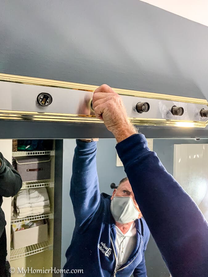 man removing light fixture parts for spray painting