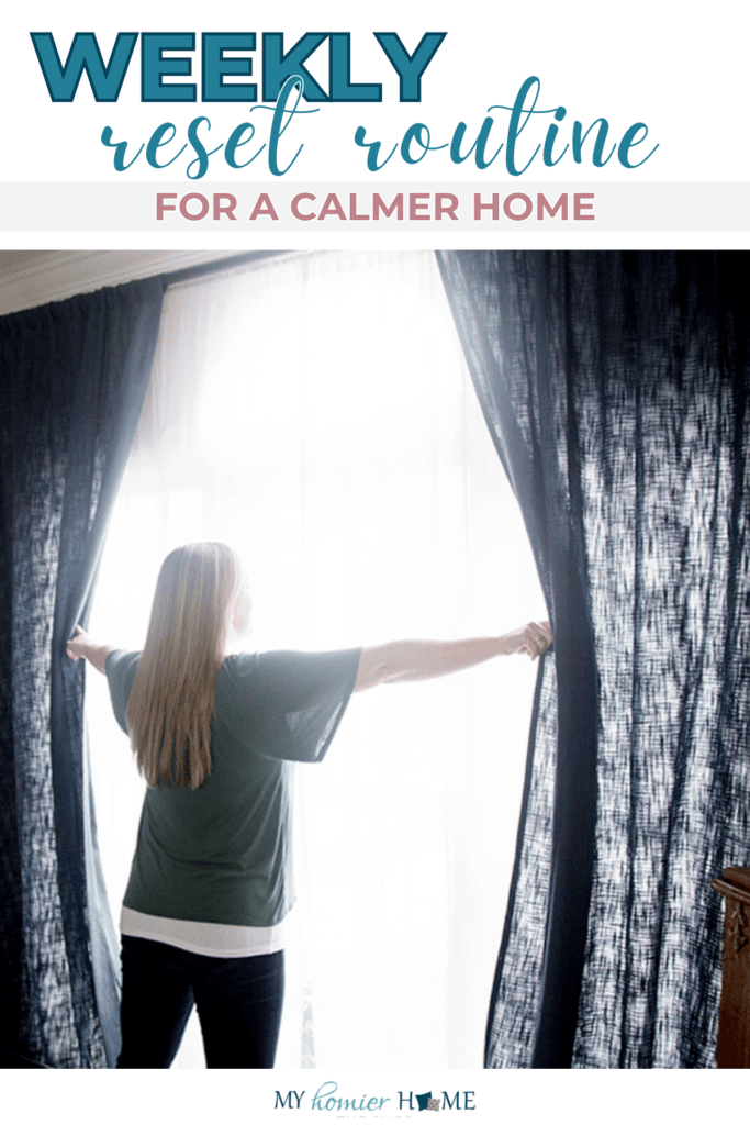 Woman opens dark blue curtains to let sunlight into a bright room, creating a peaceful atmosphere. Text above reads "Weekly reset routine for a calmer home," highlighting how small habits can bring lasting home calm.